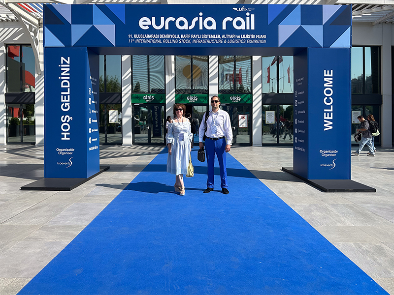 Der CEO der OKOndt Group und ein Spezialist der OKOndt Group stehen am Eingang zur Ausstellungshalle Eurasia Rail 2025 in Istanbul